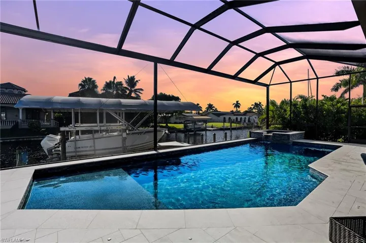 View of swimming pool featuring a water view, glass enclosure, and a sunroom