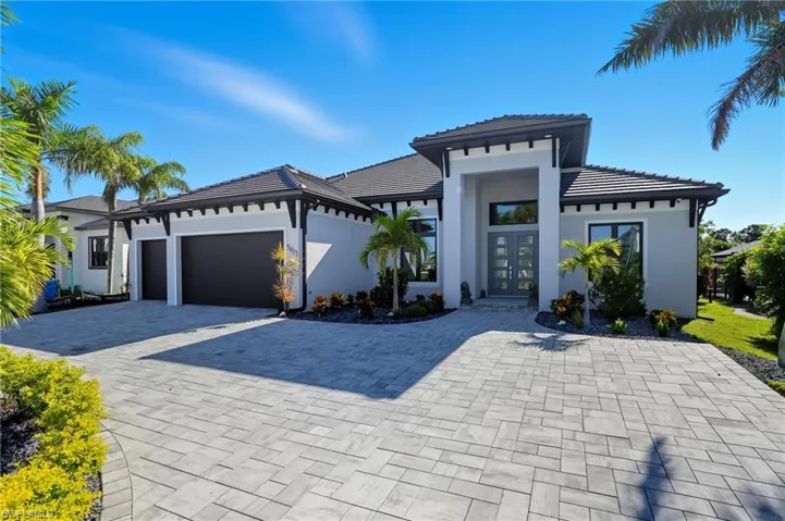 Prairie-style house featuring french doors, a tiled roof, an attached garage, decorative driveway, and stucco siding