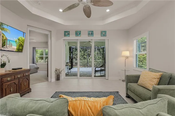 Living room with crown molding, ceiling fan, a raised ceiling, and light tile patterned floors