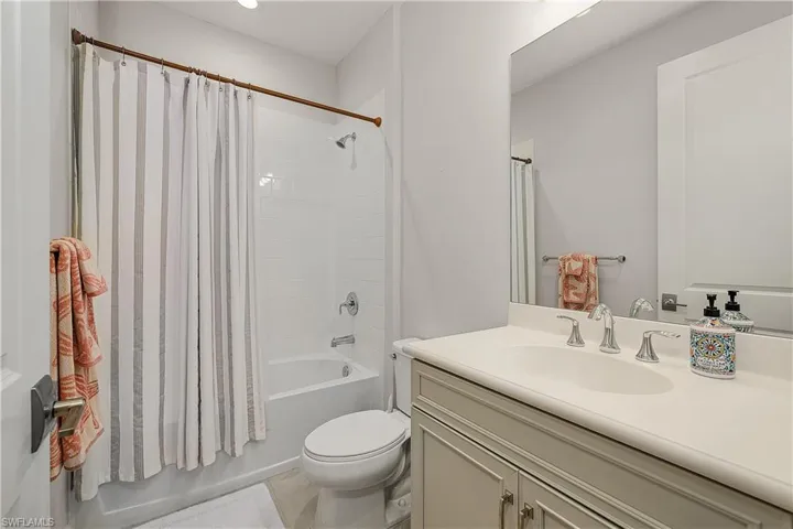 Full bathroom with vanity, shower / bath combo, toilet, and tile patterned flooring