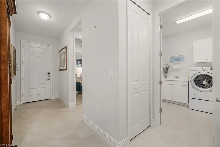 Laundry room with washer / clothes dryer, light tile patterned floors, and cabinets