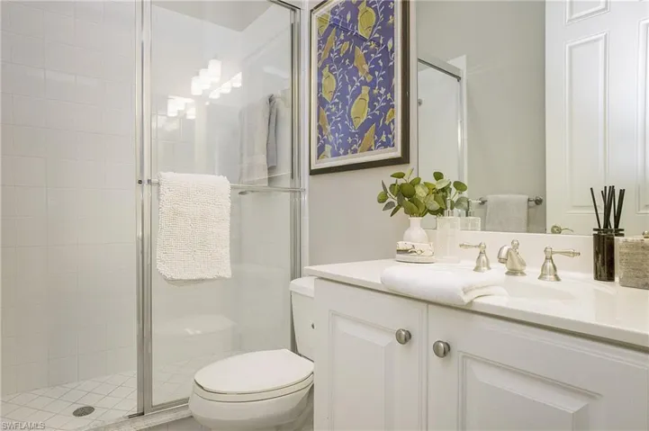 Bathroom with toilet, a shower with door, and vanity
