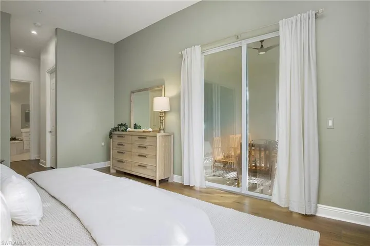 Bedroom featuring dark wood-type flooring, ensuite bath, and access to outside