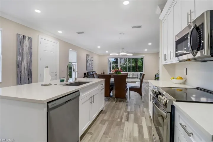 Kitchen with a center island, upgraded white cabinetry, stainless steel appliances and light wood-style flooring