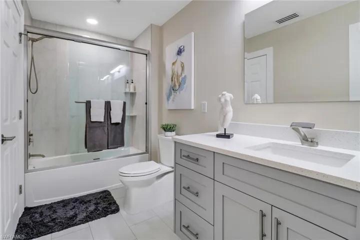 Full bathroom with vanity, toilet, tile patterned floors, and combined bath / shower with glass door