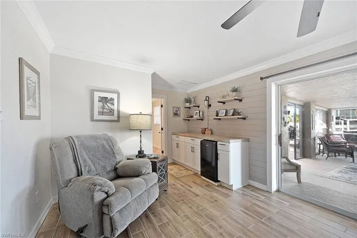 Living area featuring ceiling fan, wood walls, and ornamental molding