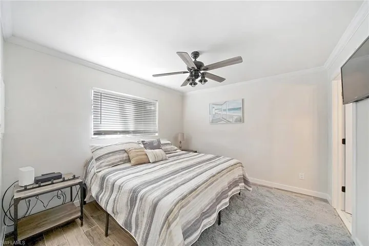 Bedroom featuring ceiling fan, crown molding, and light wood-type flooring