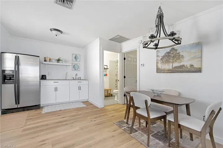 Dining area featuring light hardwood / wood-style floors, crown molding, a notable chandelier, and sink