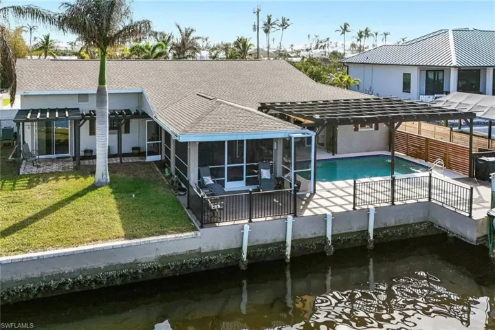 Rear view of property with a pergola, covered patio, the  yard, and a water view