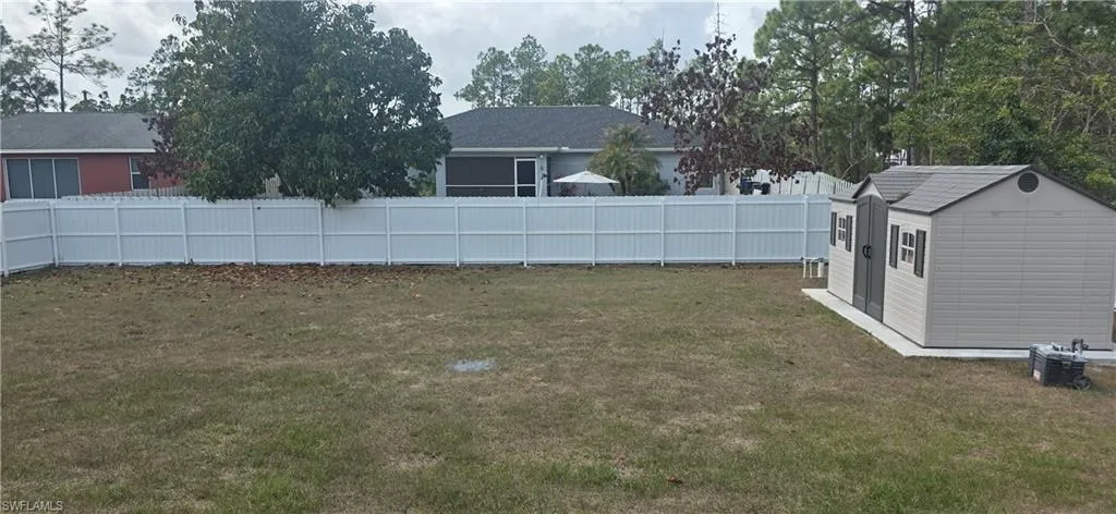 Fenced backyard featuring a storage shed