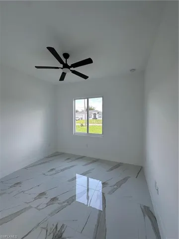 Unfurnished room featuring light marble finish flooring and baseboards