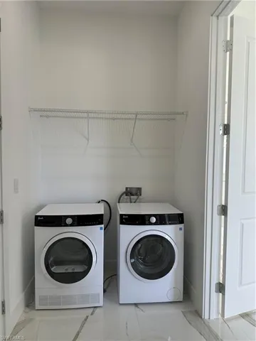 Laundry room with washing machine and clothes dryer and light marble finish flooring