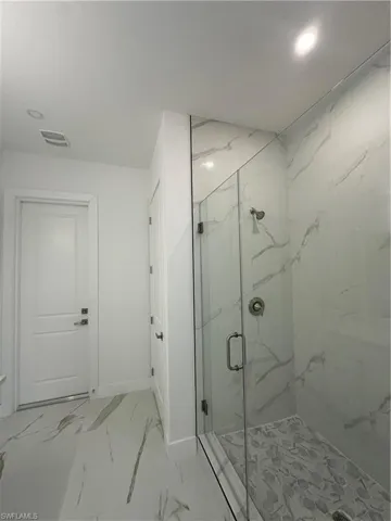 Bathroom featuring a marble finish shower and light marble finish floors