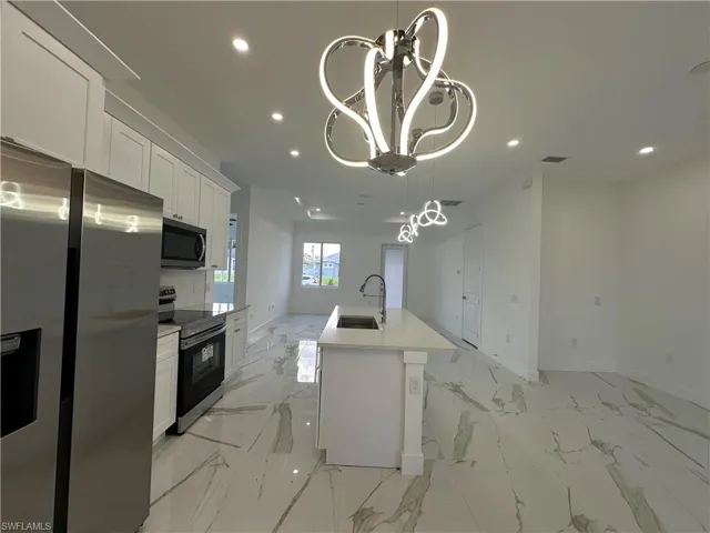 Kitchen with appliances with stainless steel finishes, white cabinetry, open floor plan, a center island with sink, and recessed lighting