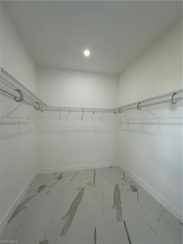 Walk in closet featuring light marble finish flooring