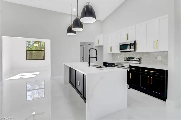 Kitchen featuring a sink, tasteful backsplash, a towering ceiling, stainless steel appliances, and dark cabinets
