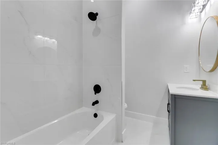 Bathroom with toilet, vanity, shower / bath combination, and baseboards
