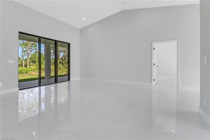 Unfurnished room featuring marble finish floor, baseboards, and vaulted ceiling