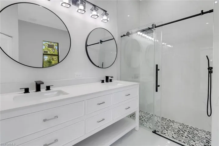 Bathroom featuring double vanity, a stall shower, and a sink