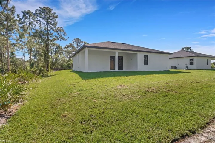 Back of house featuring cooling unit, a lawn, and stucco siding
