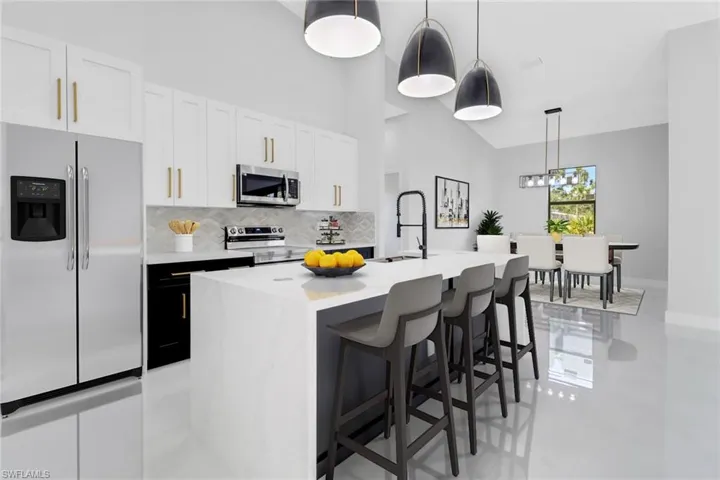 Kitchen with decorative backsplash, light countertops, appliances with stainless steel finishes, an island with sink, and a sink