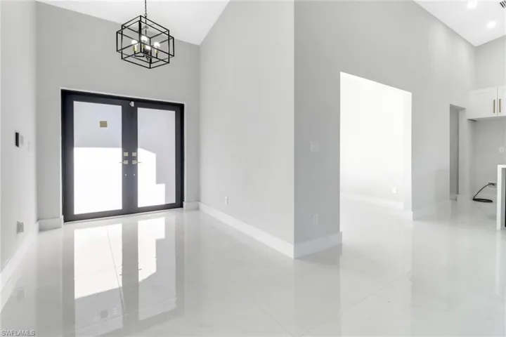 Spare room featuring a chandelier, marble finish floor, baseboards, and a towering ceiling