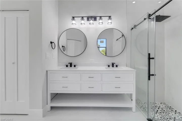 Bathroom featuring a sink, a stall shower, and double vanity
