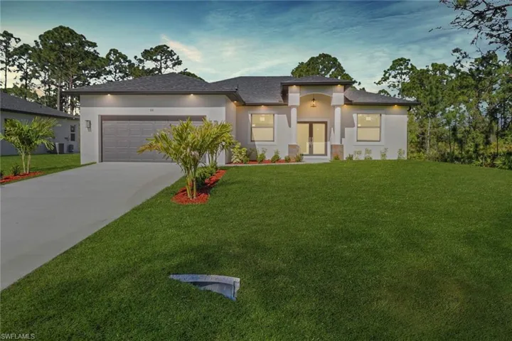 Prairie-style home with stucco siding, driveway, an attached garage, and a front lawn