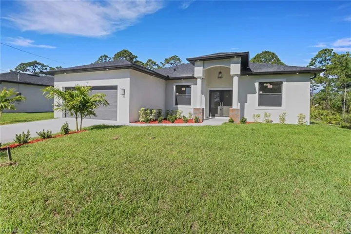 Prairie-style home with stucco siding, an attached garage, concrete driveway, and a front lawn
