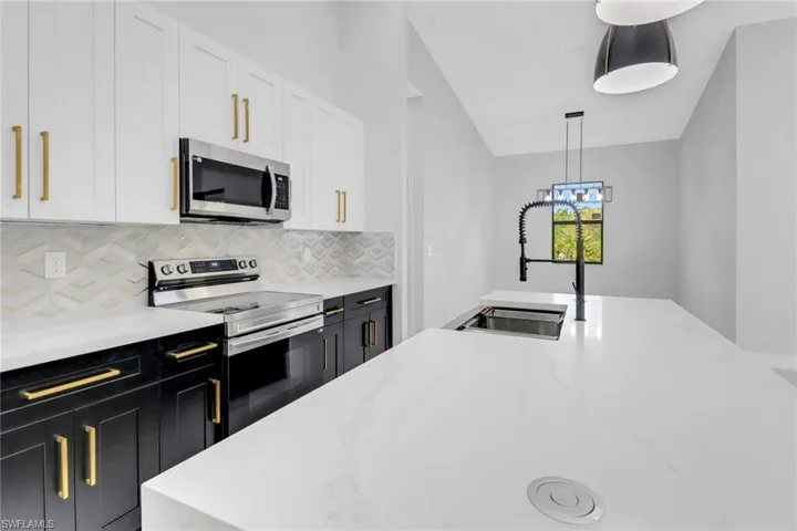 Kitchen featuring pendant lighting, a sink, stainless steel appliances, white cabinets, and decorative backsplash