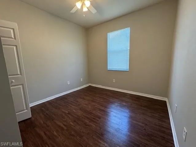Unfurnished room featuring dark wood-type flooring and a ceiling fan
