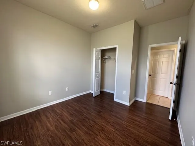 Unfurnished bedroom featuring dark wood-style floors, a closet, and a textured ceiling