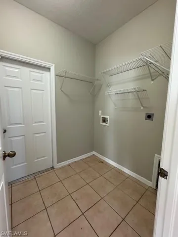 Laundry room with light tile patterned floors, hookup for a washing machine, and hookup for an electric dryer