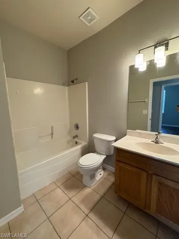 Bathroom featuring bathtub / shower combination, vanity, light tile patterned flooring, and a textured wall