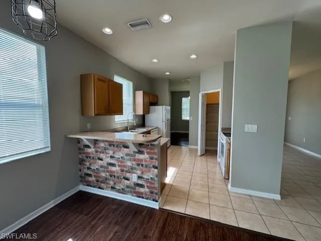 Kitchen featuring a peninsula, light countertops, recessed lighting, brown cabinets, and electric range