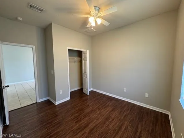 Unfurnished bedroom featuring dark wood finished floors, a ceiling fan, and a closet