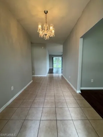 Empty room featuring light tile patterned flooring and a chandelier