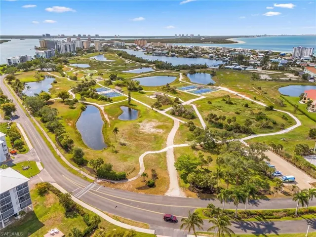 Expansive green space featuring multiple ponds, paved pathways, and tennis courts