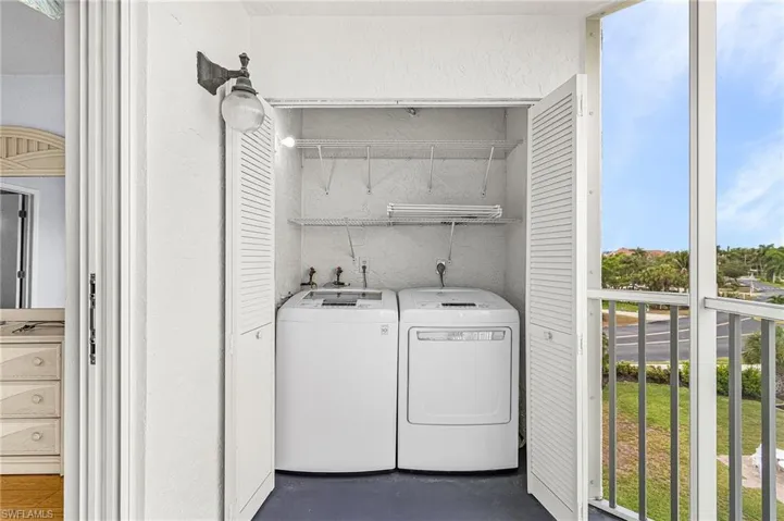 Dedicated laundry area featuring a washer and dryer, upper storage shelving, and louvered bifold doors