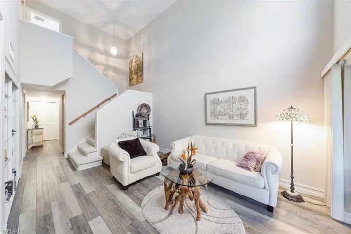 Living room with a high ceiling, wood finished floors, and stairs