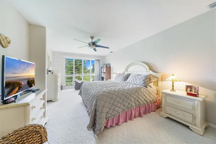 Bedroom with light colored carpet and a ceiling fan