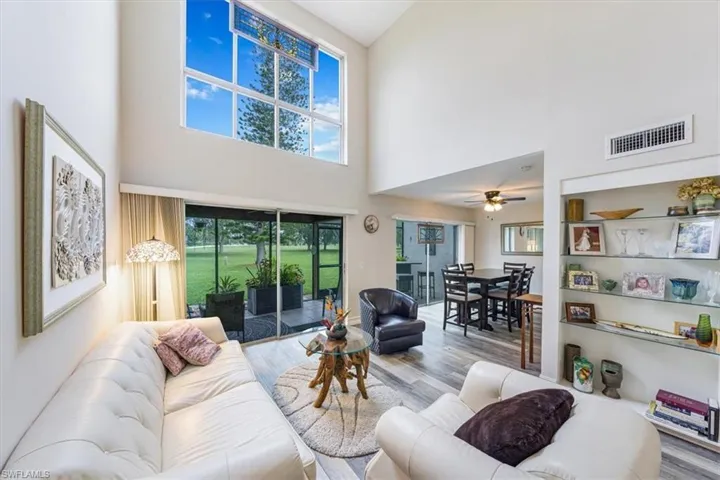 Living room with a towering ceiling, wood finished floors, and ceiling fan