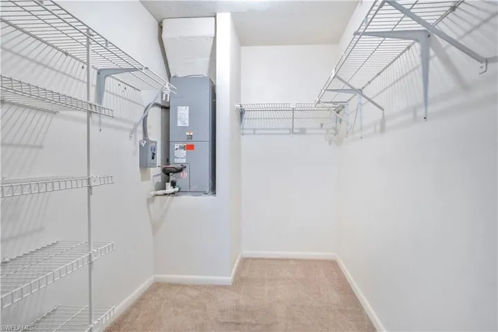 Walk in closet featuring light colored carpet and heating unit