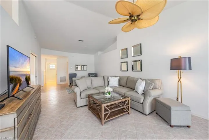 Tiled living room featuring lofted ceiling and ceiling fan