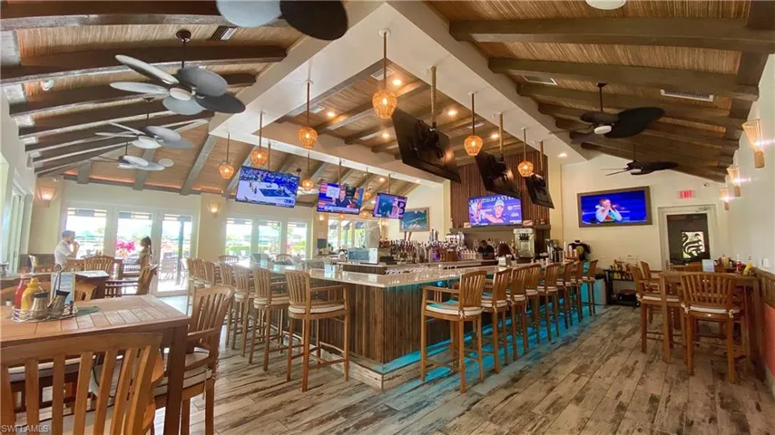 Bar with beamed ceiling, hardwood / wood-style floors, ceiling fan, and high vaulted ceiling