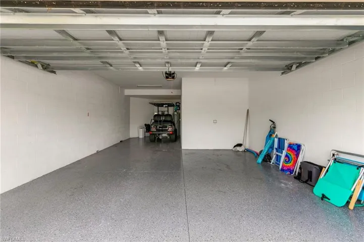 Spacious garage featuring a durable epoxy floor coating, painted block walls, and a visible garage door opener mechanism