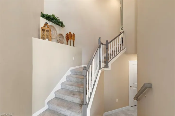 Carpeted staircase featuring painted balusters and dark-toned handrails