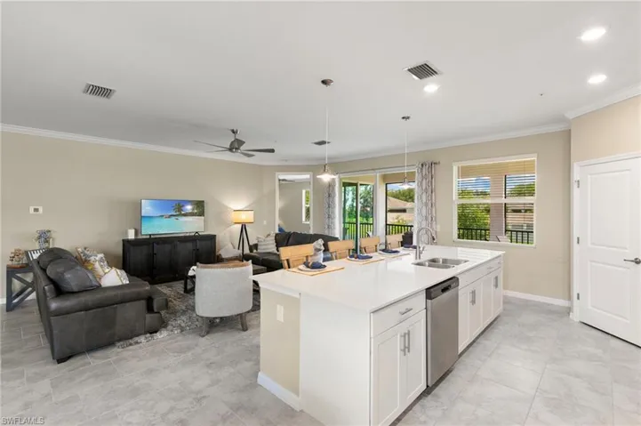 Spacious open-concept living area featuring a kitchen island with seating, stainless steel appliances, recessed lighting, and tile flooring