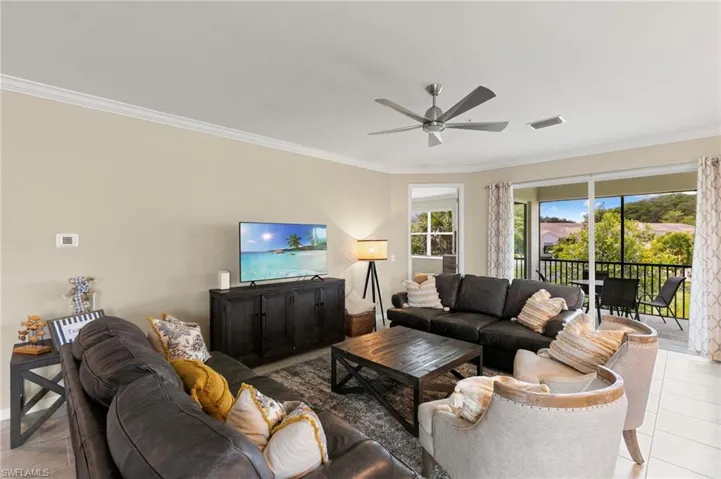Spacious living area featuring neutral wall tones, crown molding, and a ceiling fan