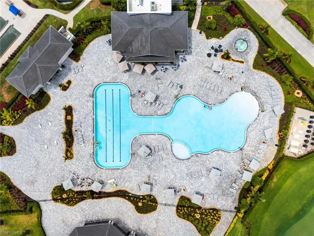 Expansive outdoor recreational area featuring a large freeform pool with integrated lap lanes, extensive paver decking, and multiple lounge areas